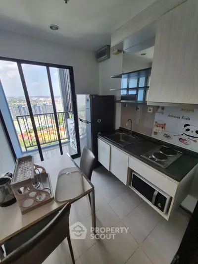 Modern kitchen with balcony view, featuring sleek appliances and ample natural light.