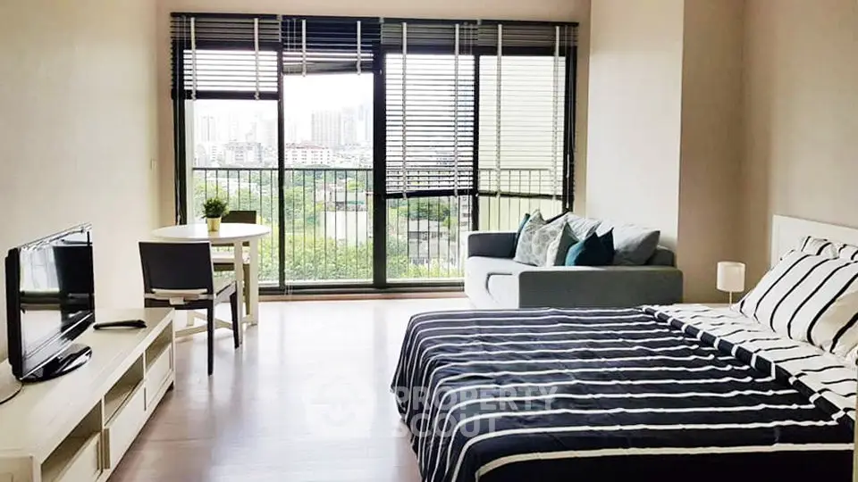 Spacious studio apartment with modern decor and city view, featuring a cozy living area and large windows.