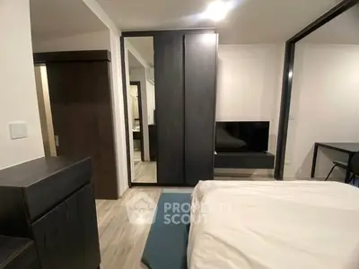 Modern bedroom with sleek furniture and mirrored wardrobe in a stylish apartment.