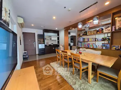 Spacious living room with wooden flooring, dining area, and built-in bookshelves in modern apartment.