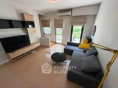 Modern living room with sleek furniture and large TV, featuring a cozy sofa and stylish decor.