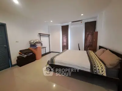 Spacious bedroom with modern decor and ample natural light, featuring a comfortable bed and minimalist furnishings.