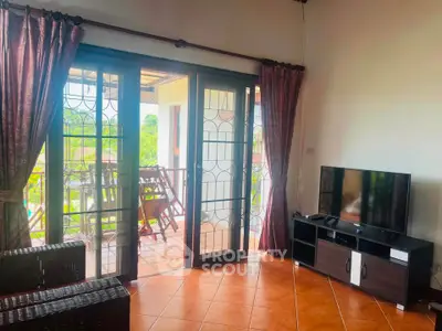 Charming living room with balcony access and natural light, perfect for relaxation and entertainment.
