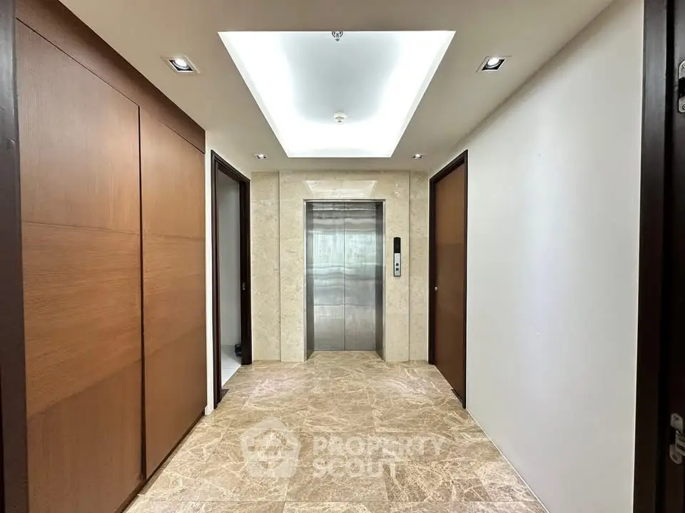 Modern building elevator lobby with elegant marble flooring and wooden paneling.