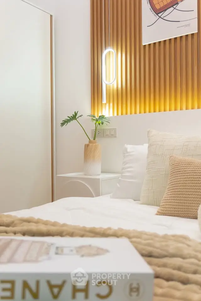 Cozy bedroom with modern decor and warm lighting, featuring stylish wall paneling and plush bedding.