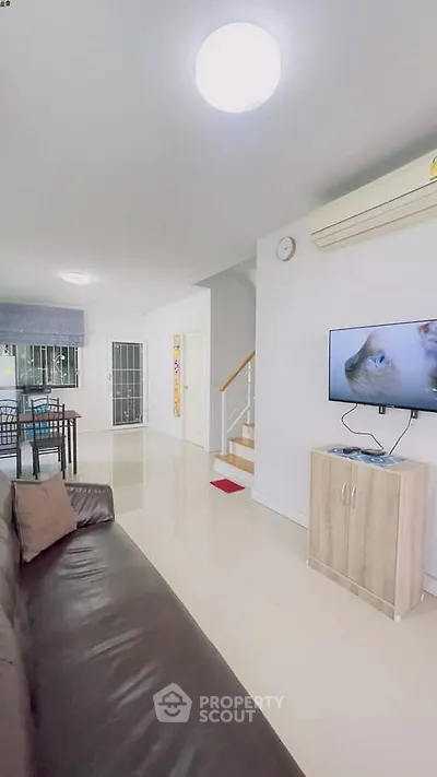 Spacious living room with modern decor and open layout, featuring a wall-mounted TV and sleek furniture.