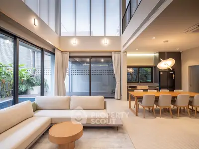 Luxurious modern living room with high ceilings and elegant dining area, featuring large windows and stylish decor.