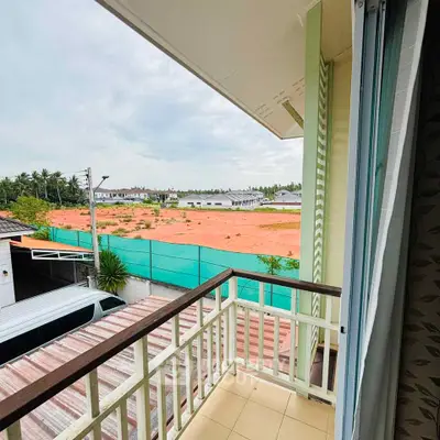 Charming balcony view overlooking a serene construction site with lush greenery and open skies.
