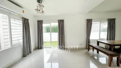Spacious living room with natural light and garden view, featuring modern decor and elegant curtains.