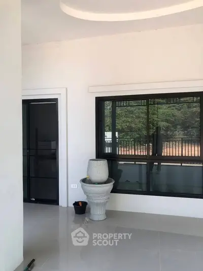 Spacious modern balcony with sleek black-framed windows and elegant planter, offering serene outdoor views.