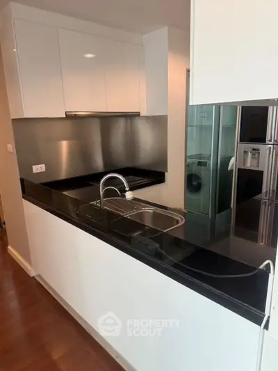 Modern kitchen with sleek black countertop and stainless steel appliances.