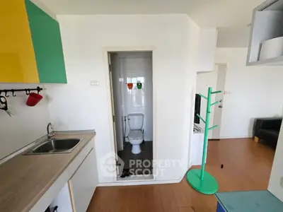 Compact apartment with open kitchen and small bathroom, featuring colorful cabinets and modern design.
