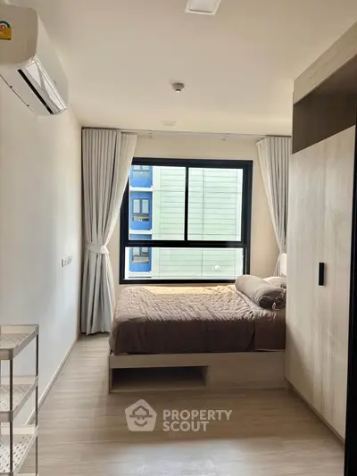 Modern bedroom with large window and neutral decor in a stylish apartment.