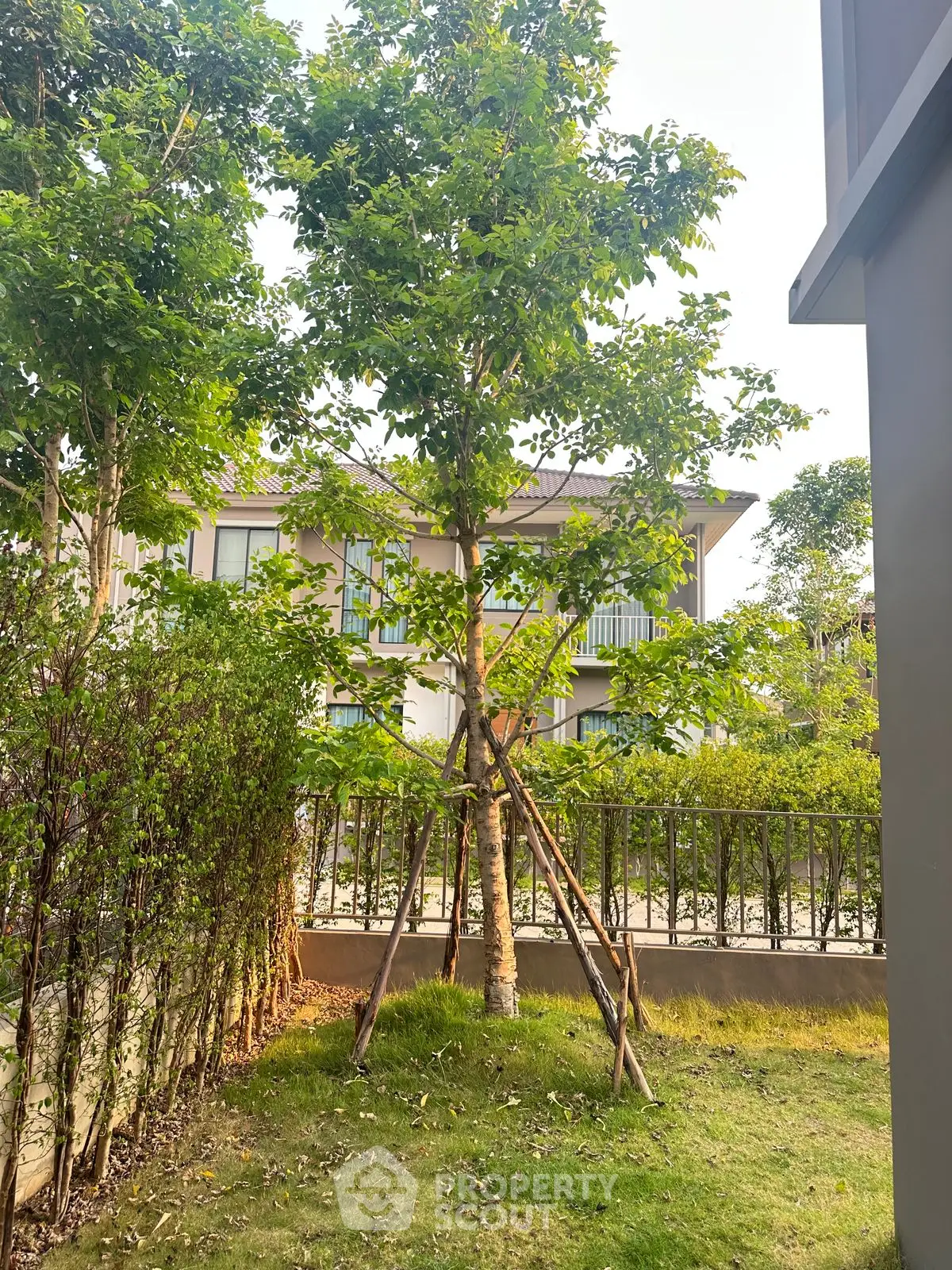 Charming garden view with lush greenery and modern building backdrop, perfect for serene living.