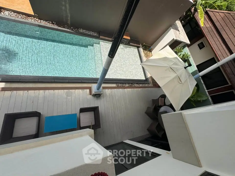 Luxurious outdoor pool area with modern seating and umbrella, perfect for relaxation and entertainment.