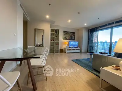 Spacious modern living room with city view, featuring stylish furniture and large windows.