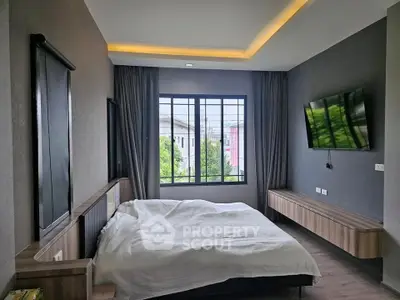 Modern bedroom with large window and wall-mounted TV, featuring sleek design and natural light.