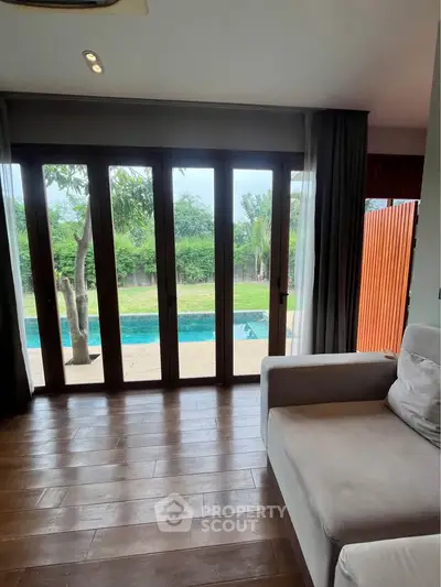 Luxurious living room with pool view and elegant wooden flooring, perfect for relaxation and entertainment.