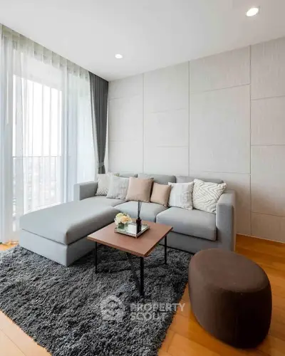 Modern living room with stylish gray sofa, cozy rug, and large windows for natural light.