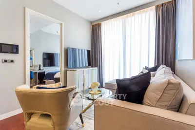 Modern living room with elegant decor and large window, featuring a cozy sofa and stylish armchair.