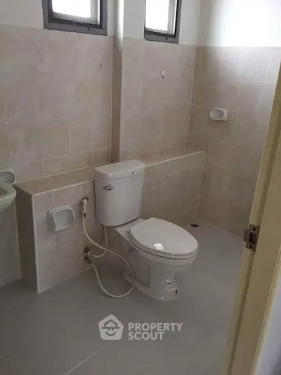 Spacious bathroom with modern toilet and tiled walls, ideal for comfort and functionality.