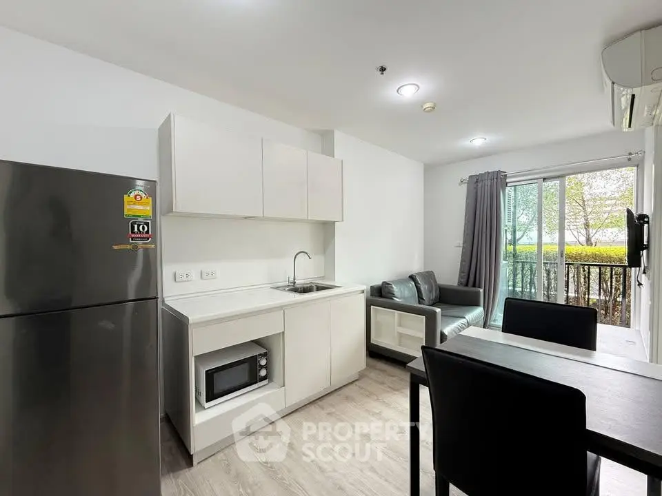 Modern open-layout kitchen and living room with sleek furniture and large window view.