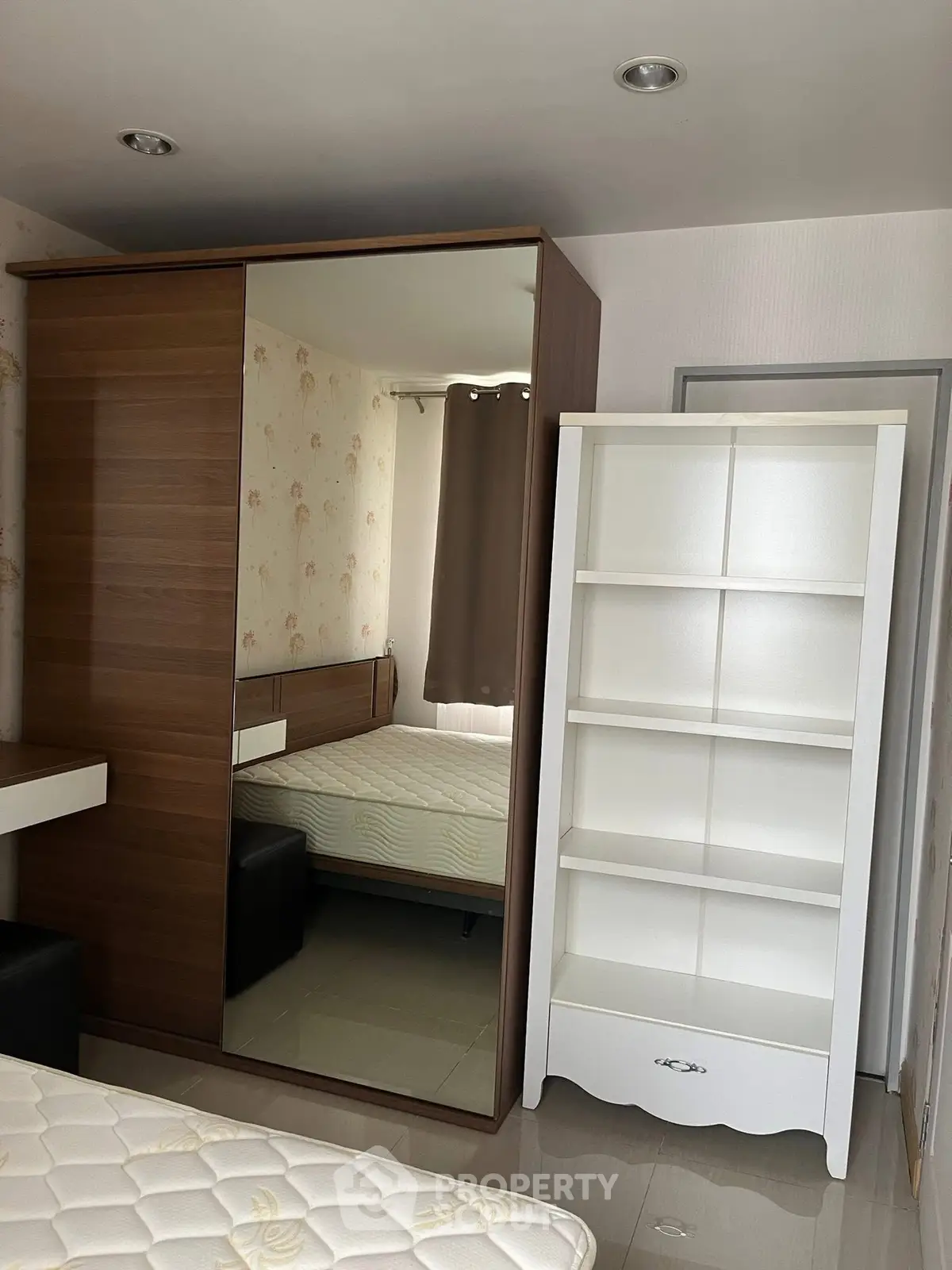 Cozy bedroom with mirrored wardrobe and white bookshelf, perfect for modern living.