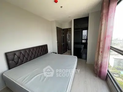 Spacious bedroom with large window offering stunning city views, featuring modern decor and ample natural light.