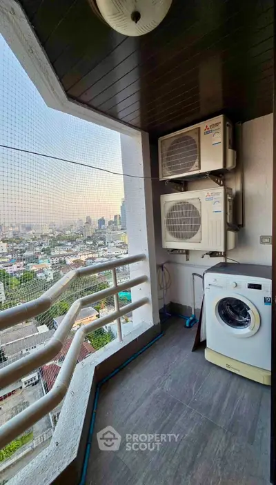 High-rise balcony with city view, featuring air conditioning units and washing machine.