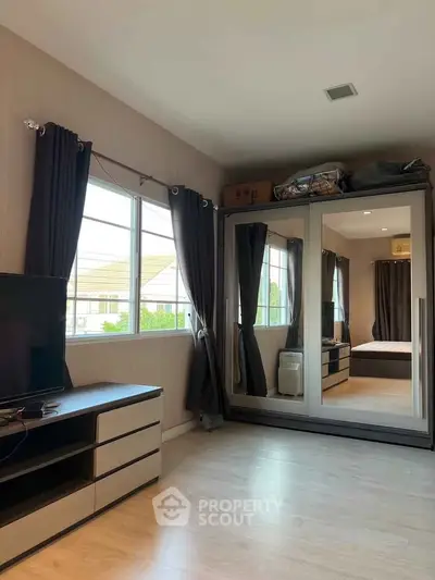 Spacious bedroom with mirrored wardrobe and natural light