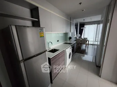 Modern kitchen with sleek appliances and open layout leading to dining area.