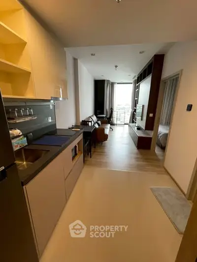 Modern apartment interior with open kitchen and living area, featuring sleek design and natural light.