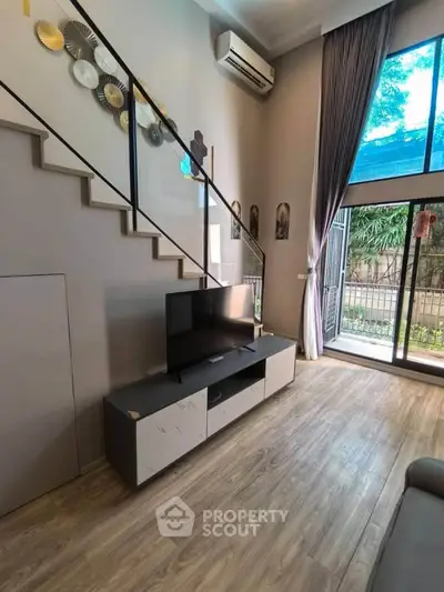Modern living room with high ceiling, large window, and stylish decor