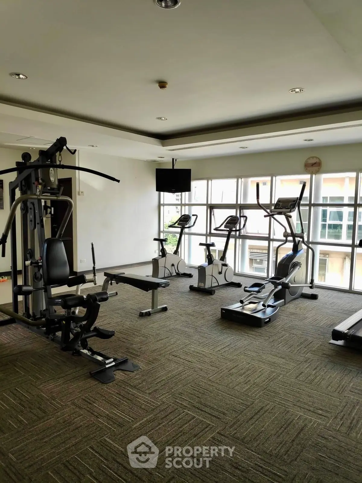 Spacious gym with modern exercise equipment and large windows for natural light.
