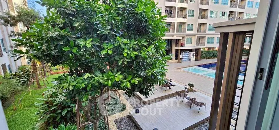 Modern apartment complex with lush garden and inviting pool area view.