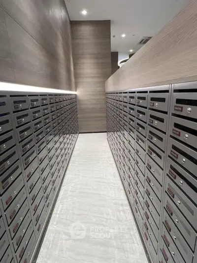 Modern apartment building mailroom with sleek metal mailboxes and bright lighting.