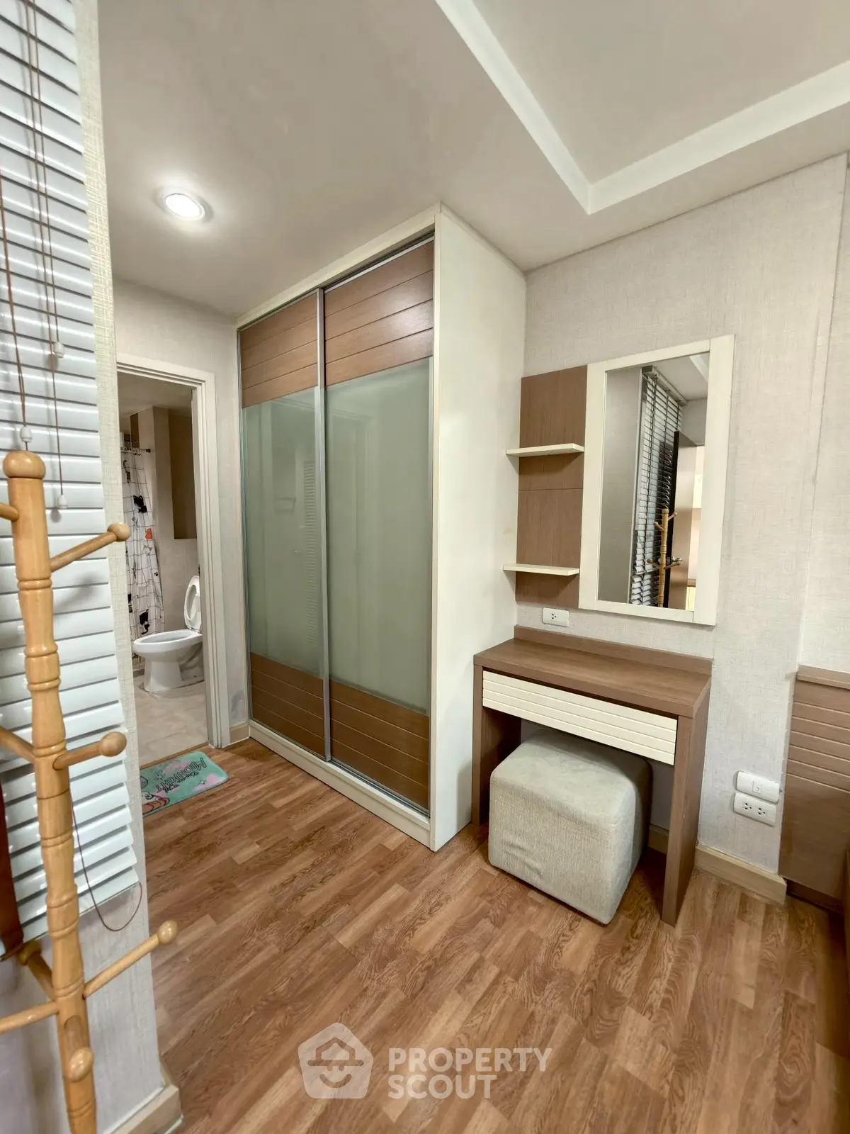 Stylish bedroom with modern wardrobe and vanity in cozy apartment