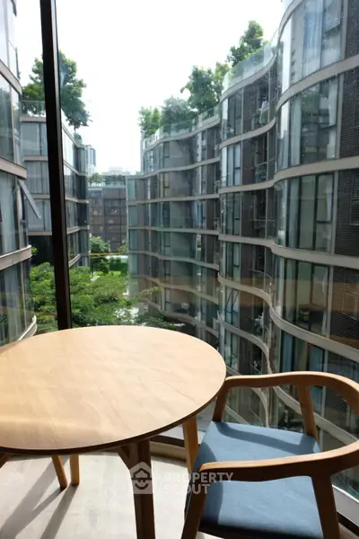 Modern balcony with stylish furniture overlooking contemporary architecture and lush greenery.
