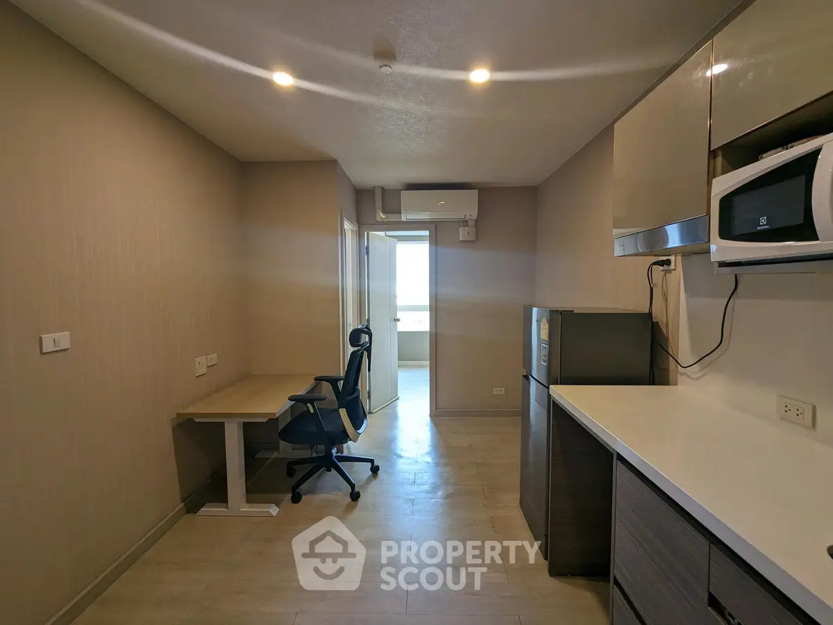 Modern study room with desk, chair, and appliances in a sleek apartment