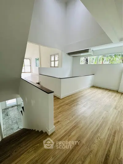 Spacious modern interior with wooden flooring and ample natural light, perfect for stylish living.