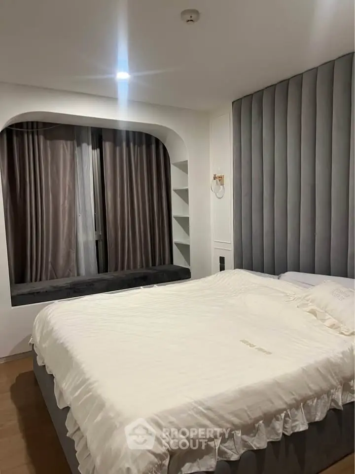 Modern bedroom with stylish headboard and cozy window seating in a contemporary apartment.