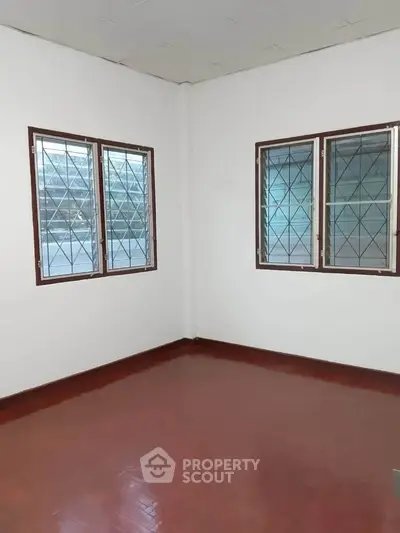 Spacious empty room with large windows and polished wooden floor, perfect for customization.