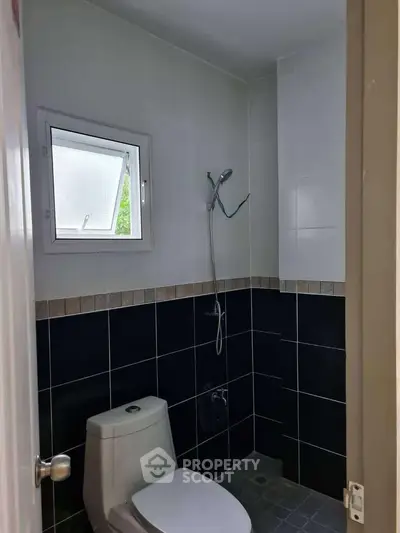 Modern bathroom with sleek black tiles and compact shower area.