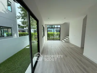 Modern interior with large windows and garden view, showcasing sleek flooring and open space.