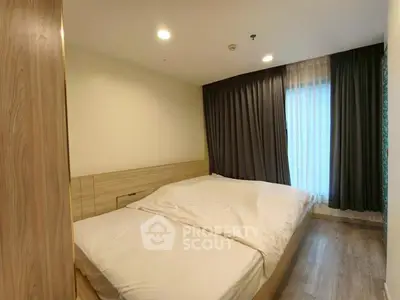 Cozy modern bedroom with wooden flooring and large window, perfect for relaxation.
