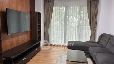 Modern living room with sleek furniture and large window offering natural light.