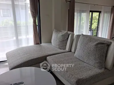 Spacious living room with modern sofa and large windows offering natural light.