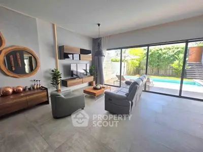 Spacious modern living room with pool view, elegant decor, and large sliding glass doors.