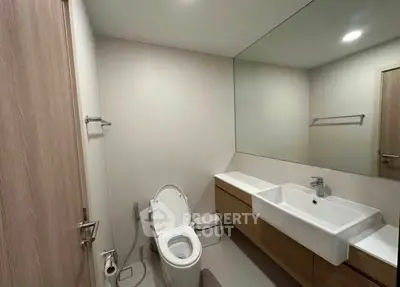 Modern bathroom with sleek fixtures and large mirror in a contemporary home.