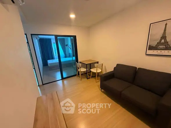 Modern living room with cozy sofa and dining area, featuring a view into the bedroom.